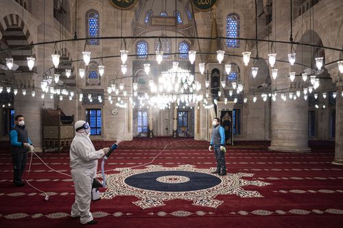 Workers wearing protective clothing disinfect a historical mosque, in Istanbul, Wednesday, March 11, 2020