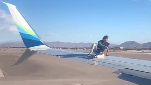 An image from video shot by a passengers shows the man sitting on the wing of the Alaska Airlines jetliner.