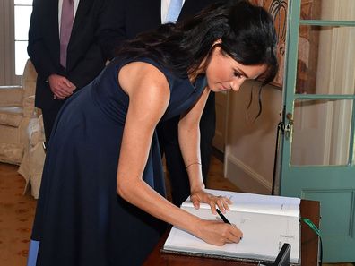 The Duchess of Sussex signing a visitor's book