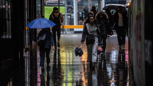 People on their way to work in Melbourne on Wednesday as the rain starts to hit. 