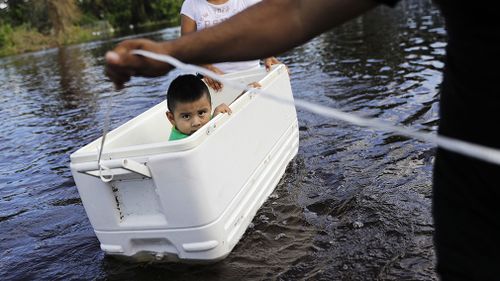 Alfonso Jose Jr., 2, is floated down his flooded street by his parents as the wade through water to reach an open convenience store in the wake of Hurricane Irma in Bonita Springs. (Associated Press)