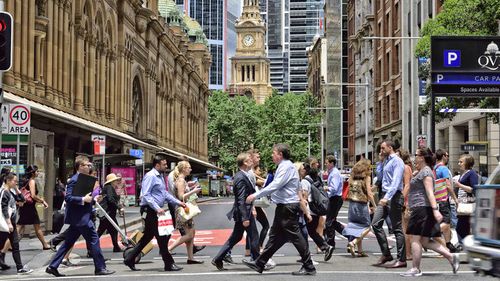 Trabalhadores atravessam a rua no CBD de Sydney.  