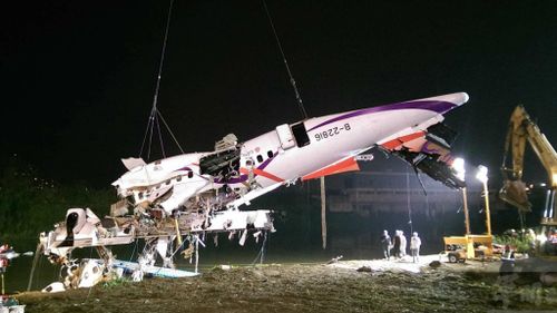 The tail section of the plane is lifted by a crane from the river. (AAP)
