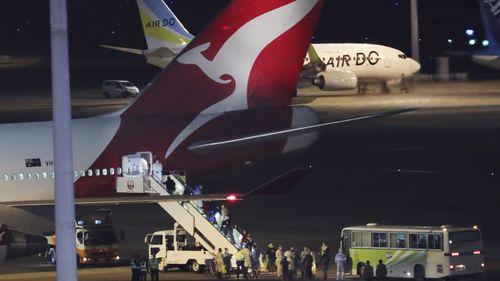 Passengers from the quarantined Diamond Princess cruise ship board an airplane at Haneda airport in Tokyo Wednesday, Feb. 19, 2020. 