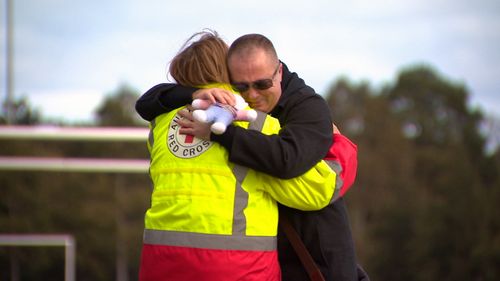 A local man hugs a Red Cross worker at the scene of Ms Dixon's murder. (9NEWS)