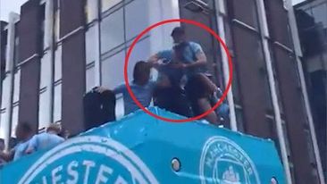 Teammates catch Jack Grealish before he falls off the Manchester City bus.