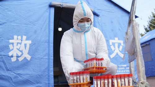 A worker in protective clothing handles COVID-19 test samples in Bayan County of Harbin city in northeastern China's Heilongjiang Province. 