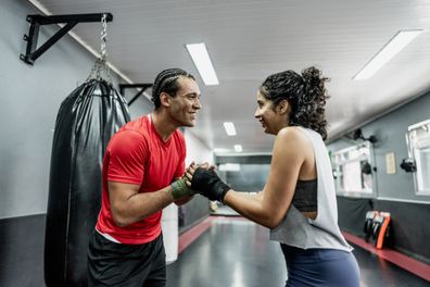 Boxe instructor and mid adult woman greeting at gym