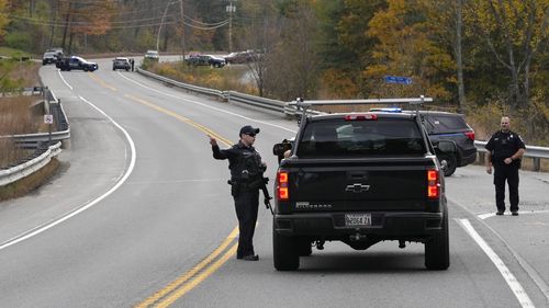 Police officers speak with a motorist at a roadblock, Thursday, Oct. 26, 2023, in Lisbon, Maine