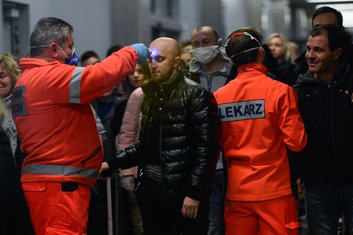 A health worker screens the temperature of a passenger arriving from Milan Bergamo to Krakow International Airport on February 26, 2020.