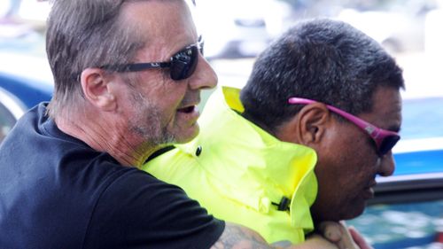 AC/DC drummer Phil Rudd jumps on his security guard's back outside court in New Zealand. (AFP)