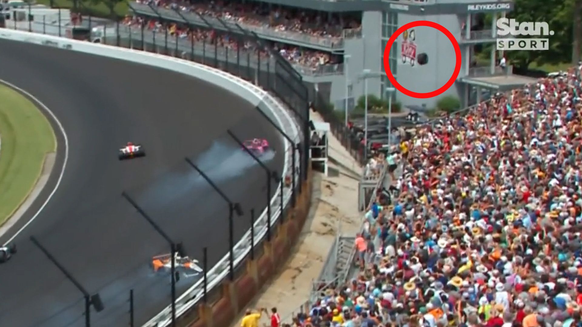 A wheel from Kyle Krikwood&#x27;s car flies out of the confines of the race track, narrowly avoiding the packed grandstand.