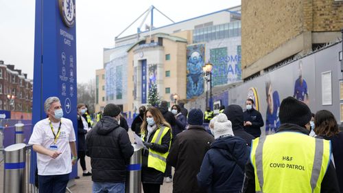 People walk for their vaccination into Stamford Bridge Stadium, at Chelsea, in London, Saturday, Dec. 18, 2021. 