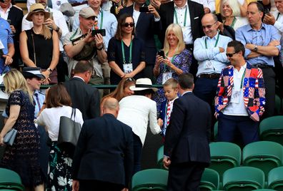 Duchess of Sussex shakes hands with a young spectator dressed in Star Spangled Banner attire on the day.