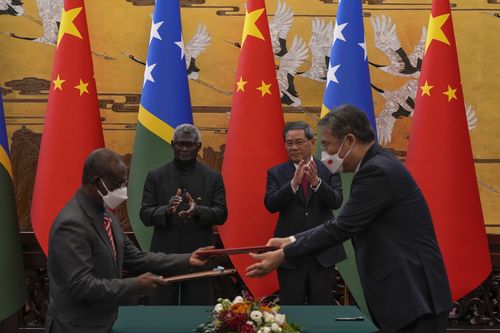 Visiting Solomon Islands Prime Minister Manasseh Sogavare, center left, and Chinese Premier Li Qiang, center right, applaud as both countries' officials exchange signed documents at the Great Hall of the People in Beijing, Monday, July 10, 2023.