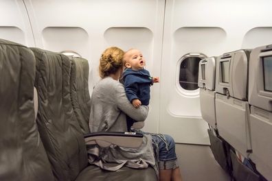 Caucasian mature Woman traveling with her baby sitting in an airplane cabin