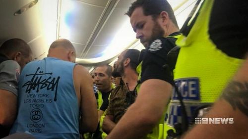 A group of passengers on board a Garuda Indonesia flight bound for Perth were forced to step in and strap down a couple on board the plane.