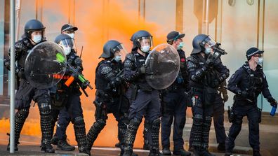 Police have bottles and flares thrown towards them during a protest at the CFMEU headquarters in Melbourne,  on Monday.