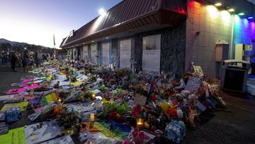 Mourners gather outside Club Q to visit a memorial, which has been moved from a sidewalk outside of police tape that was surrounding the club, on Friday, Nov. 25, 2022, in Colorado Spring, Colorado  