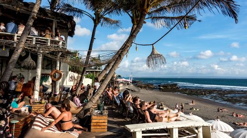 Wisatawan berjemur di bawah sinar matahari di restoran pantai di Kali, Bali.