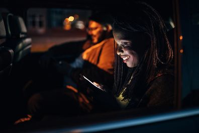 Man and woman, multi-ethnic couple sitting in a car together, ridding on back seat of a car, ride sharing in city,