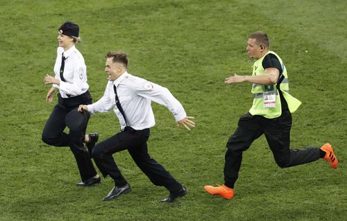 A security guard (R) chases a man and woman who invaded the pitch during the second half of the World Cup final between France and Croatia at Luzhniki Stadium in Moscow on July 15, 2018. Russian protest group and musical act Pussy Riot has claimed responsibility for the incident. (Kyodo via AP Images)