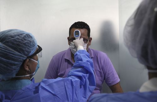 A man wearing a mask as a precautionary measure against the spread of the new coronavirus gets his temperature taken.
