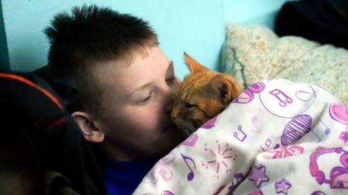 A boy and his cat hide from the Russian artillery shelling in a school basement in the village of Horenka close to Kyiv.
