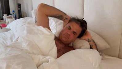 Robbie Williams waking up in bed.
