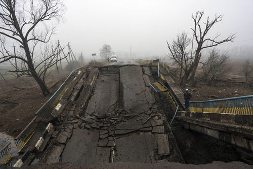 오토바이 운전자가 2022년 4월 1일 금요일 우크라이나 키예프 외곽 마을에서 러시아군에 의해 파괴된 다리를 바라보고 있습니다. (AP Photo/Rodrigo Abd)