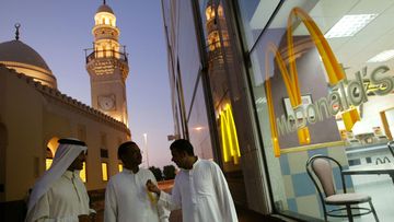 Men walk past a McDonald&#x27;s as they leave a prayer session in a mosque in Manama, Bahrain.