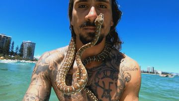 Shiva the surfing snake along with her owner Higor Fiuza at a Gold Coast beach.