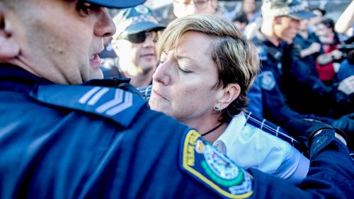 Police rush to the assistance of Christine Forster as she's caught up in protests at an event for her brother, former prime minister Tony Abbott, in Redfern, Sydney. (AAP)
