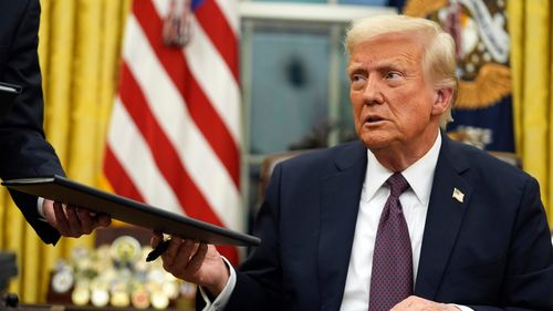 O presidente Donald Trump assina ordens executivas no Salão Oval da Casa Branca, em 20 de janeiro de 2025, em Washington.