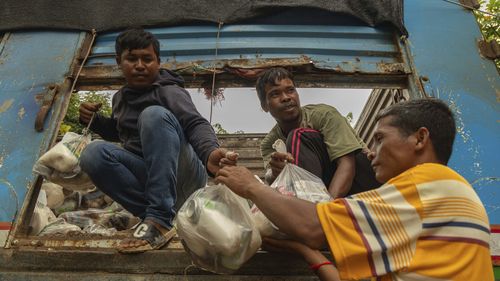 Cambodian volunteers help unload a supply truck at a resettlement camp, established to house thousands of people fleeing the Thailand-Cambodia clash,