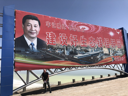 Mike Smith pictured beneath a huge poster of Xi Jinping.
