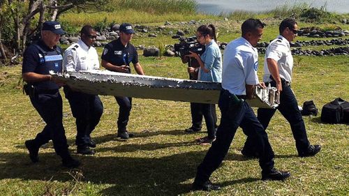 Officials carry away the debris after it was found on a beach on La Reunion.