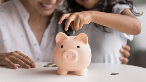 Woman and child sitting behind a piggybank
