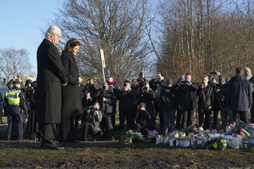 Sweden's King Carl XVI Gustaf and Queen Silvia place flowers at a memorial near the scene of a shooting on the outskirts of Orebro, Sweden, Wednesday, Feb. 5, 2025. (AP Photo/Sergei Grits)