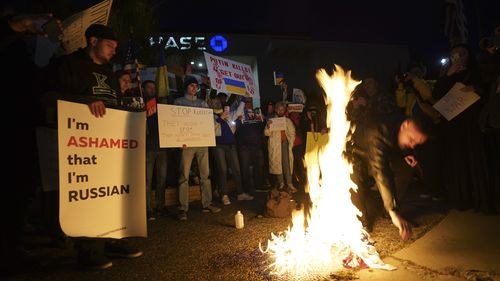 A Russian citizen burns a Russian flag as people protest the Russian invasion of Ukraine at a demonstration in the Studio City neighbourhood of Los Angeles, Thursday, Feb. 24, 2022