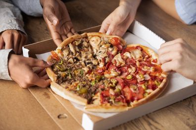 Close up hands of multi-ethnic people hungry students best friends gathered together meet in pizzeria taking sharing slices of meat pizza, girls and guys ordering italian cuisine enjoying food concept