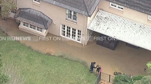 Residents can be seen trying to bail water out of their homes. (9NEWS)