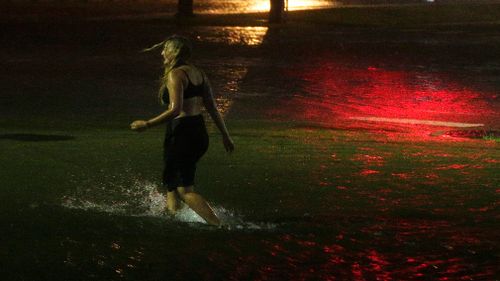 A woman wades through a flooded Water St. in downtown Mobile, during Hurricane Nate. (AAP)