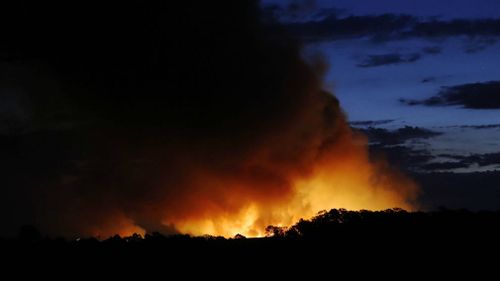 The glow of a bushfire at dusk as it burns through Richmond Vale near Cessnock in the Hunter Valley. (AAP)