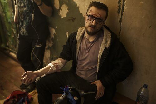 Vadim Krikun is treated in the hallway of his apartment building after a Russian attack in Kharkiv, Ukraine, Friday, April 15, 2022. (AP Photo/Felipe Dana)