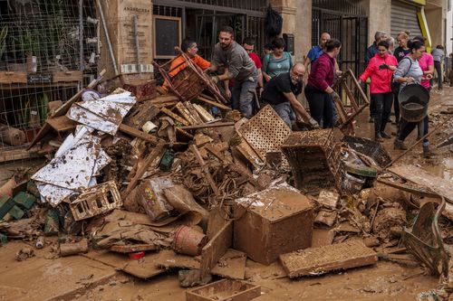 People clean mud from a shop affected by floods in Chiva, Spain, Friday, Nov. 1, 2024.