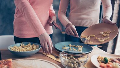 Cropped close up photo two people she her ladies arms hold dirty plates, clean wash table holiday dishes kitchen apply forks knifes prepare dining loft room sweet cookies cafe restaurant indoors