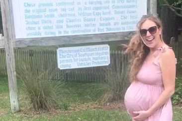Pregnant woman looking for baby name inspiration at a cemetery