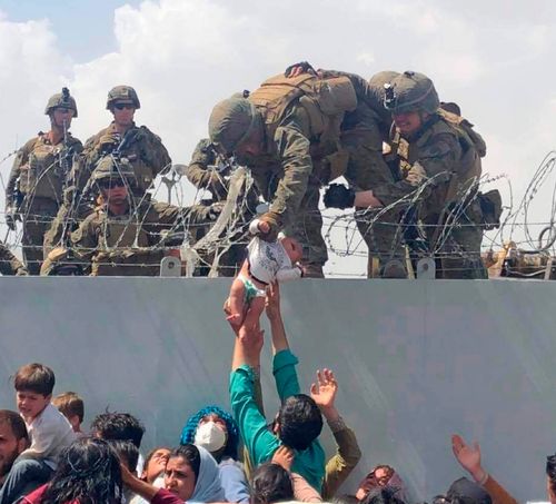 A baby being lifted across a wall at Kabul Airport in Afghanistan by US soldiers, during chaotic scenes last week.