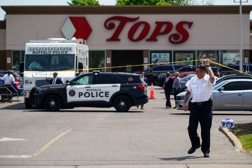 A police officer lifts the tape cordoning off the scene of the Buffalo shooting.